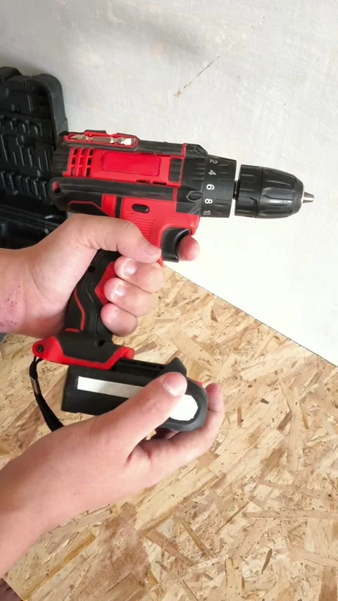 A man connects a battery to a power drill. Cordless electric drilling tools Stock Footage 322894065
