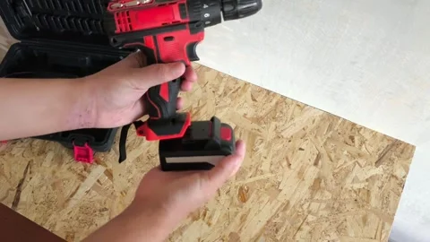 A man connects a battery to a power drill. Cordless electric drilling tools Stock Footage 322894204