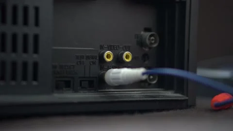 A man connects a cable to the VCR,DVD Video stock 234407745