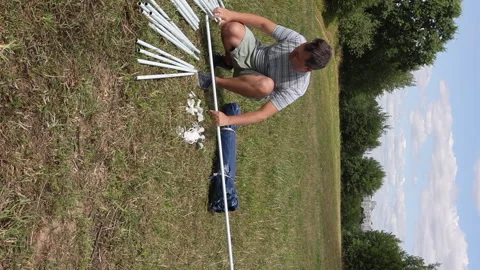 A man connects the elements of the tent with a mosquito net. Building a gar.. Stock Footage 247974262