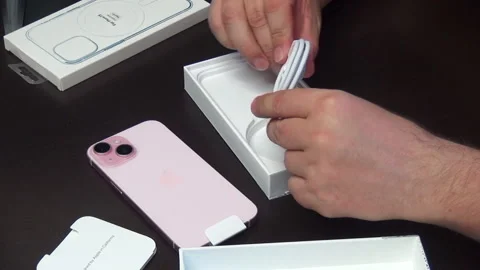 A man considers the contents of the box with iPhone 15. Makes the unpacking.. Stock Footage 277546387