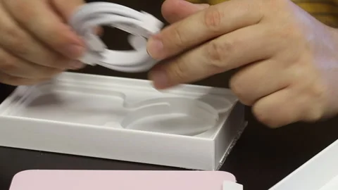 A man considers the contents of the box with iPhone 15. Makes the unpacking.. Stock Footage 277546400
