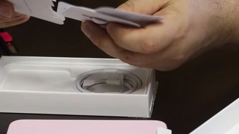 A man considers the contents of the box with iPhone 15. Makes the unpacking.. Stock Footage 277546422
