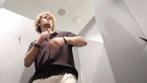 Man considers whether the shirt is worth buying before making his final choice Stock Footage 344856160