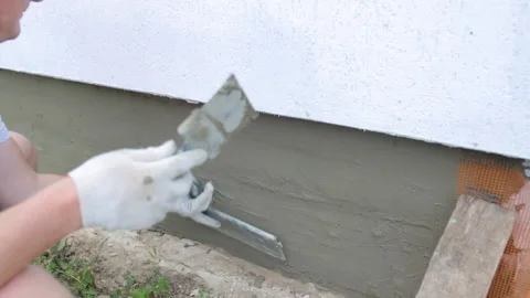 A man in construction gloves is plastering the foundation and using construction Stock-Footage 250937650