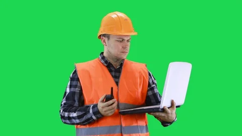 A man in a construction helmet and an orange vest is talking on a walkie-talkie Stock Footage 127976548