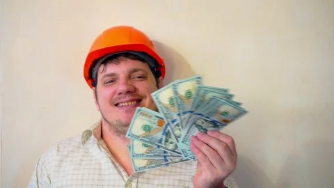 Man in a construction helmet with a stack of hundred dollar bills Stock Footage 101774591