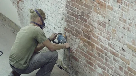 Man in a construction mask remodelling a wall Stock Footage 81043099