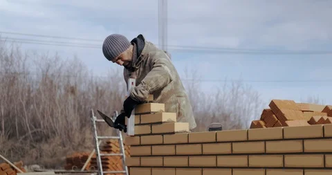 Man at construction site checks level of evenness of brickwork. Masonry. Builder Stock Footage 128939138