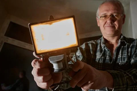 A man at a construction site demonstrates a lantern that he uses to illuminate Stock Photos