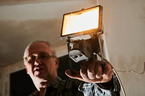 A man at a construction site demonstrates a lantern that he uses to illuminate Stock Photos