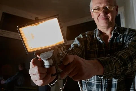 A man at a construction site demonstrates a lantern that he uses to illuminate Stock Photos