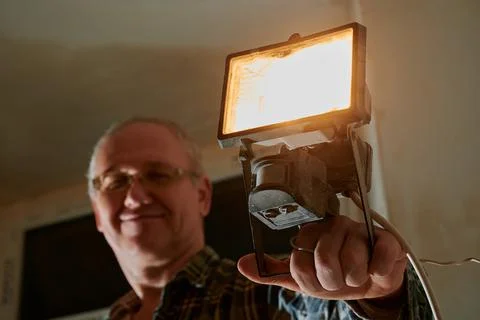 A man at a construction site demonstrates a lantern that he uses to illuminate Stock Photos