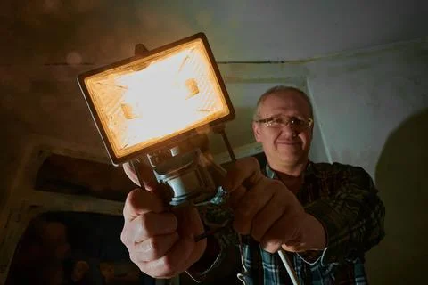 A man at a construction site demonstrates a lantern that he uses to illuminate Foto stock