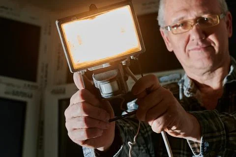 A man at a construction site demonstrates a lantern that he uses to illuminate Stock Photos