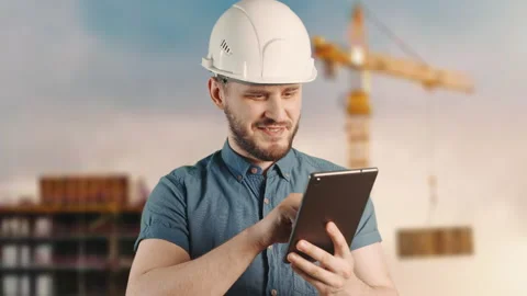 A man construction worker with helmet is smiling and using tablet at building Stock Footage 205455861