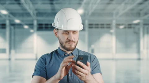 A man construction worker with helmet is using mobile phone at building site Stock Footage 204028829