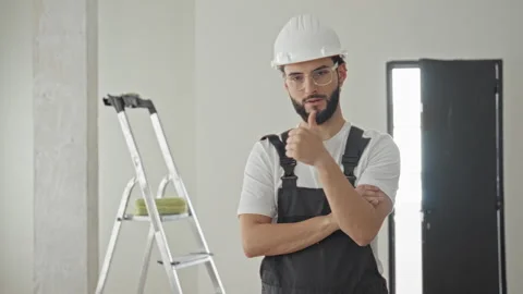 Man construction worker wearing hard hat gives thumbs up beside ladder in b.. Stock Footage 337371707