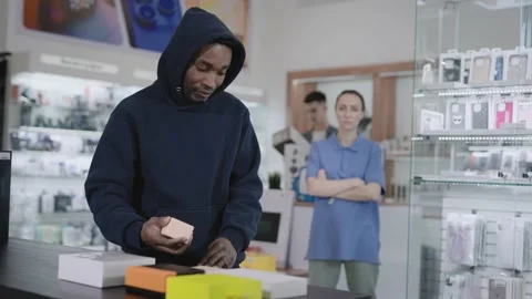 A man in a consumer electronics and gadgets store commits a theft. Crime and Stock Footage 228604172
