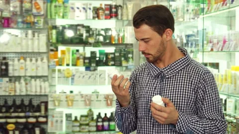 Man contemplating between two medication options in a pharmacy Video stock 311944080