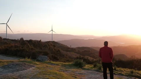 Man contemplating sunset landscape with wind turbines Stock Footage 344531179