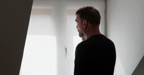 Man Contemplating by Window: Stockbeeldmateriaal 331539879