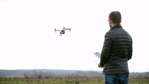 Man control drone flies in the white sky background Stock Photos