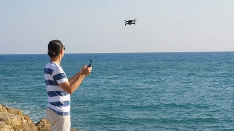 Man control small drone, send it fly to sea. Windy weather Stock Footage 105198665