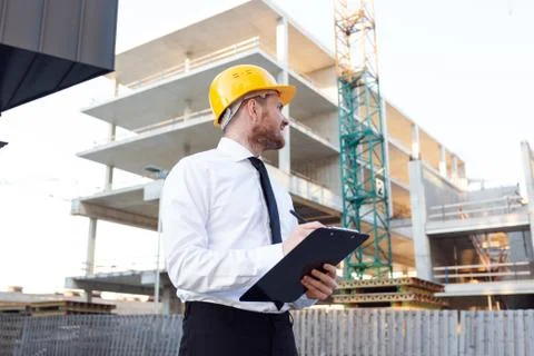 Man Controlling Building. Builder making marks in Clipboard. House Building Stock Photos