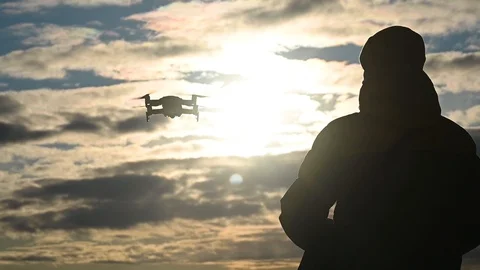 Man controls a drone against setting sun in winter Stock Footage 124147309