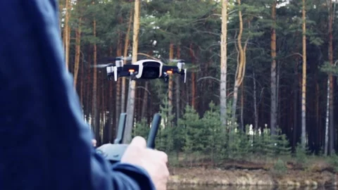 The man controls the drone from the control panel, the quadcopter hovers in the Stock Footage 154164255