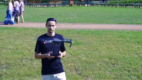 A man controls a drone on a lawn with green grass Stock Footage 80687080