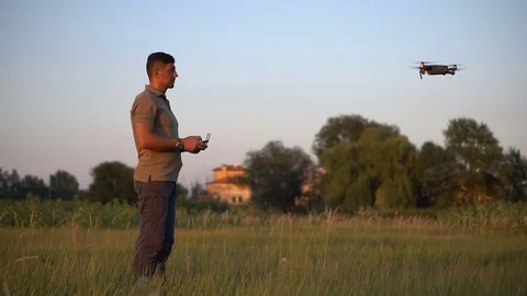 A man controls a drone on a meadow at sunset in the summer Stock Footage 79831259