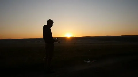 A man controls a drone at sunset Видео 62960975