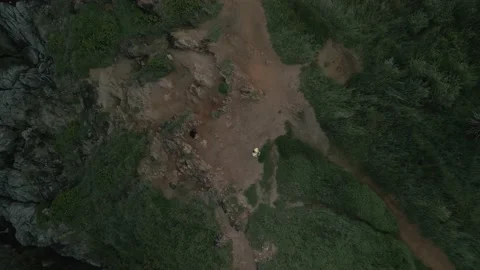 Man controls drone, takes off over person, waves wash over rocks, Stock Footage 226932664