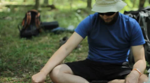 The man controls the gas burner in the forest. He is sitting on the ground and Stock Footage 64524791