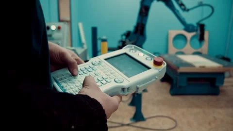 Man controls an industrial robot with a remote control Stock Footage 247368697
