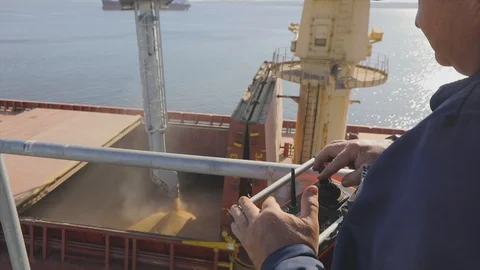 A man controls the loading of wheat into a ship. Loading wheat into a cargo ship Видео 119398164