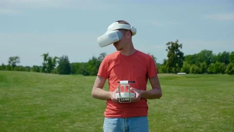 Man controls quadrocopter remote control, looks video with goggles on head Video stock 136659731