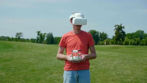 Man controls quadrocopter through remote control. Drone operator in red T-shirt Stock Footage 134601219