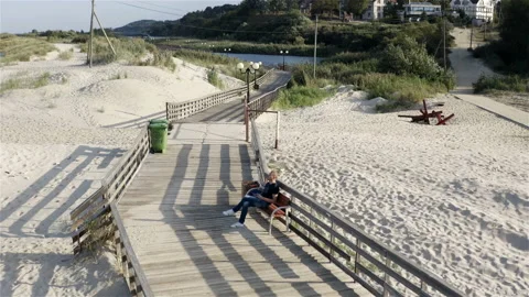 A man controls a quadrocopter while sitting on a bench by the sea Stock Footage 117630333