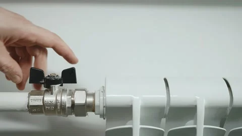 The man controls the temperature of the heater by opening the water tap. Stock Footage 222785958