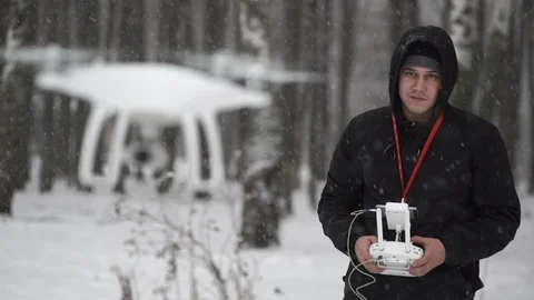Man controls a white quadcopter (drone) in a winter forest. Stock Footage 87519374