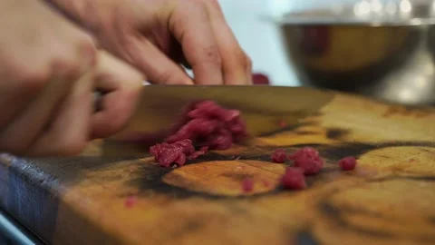 A man, a cook, in the kitchen, quickly cuts pork meat on a cutting board Stock Footage 140963197