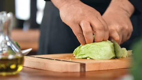 Man cook worker hand cutting green lettuce leaf on kitchen table. Close up shot Видео 124155537