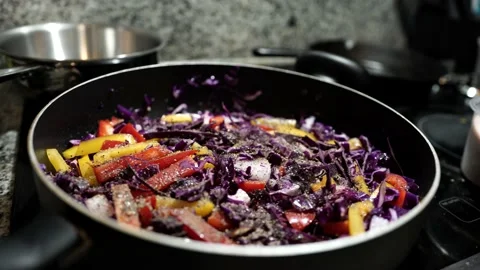 Man Cooking Adding Seasoning and Salt to Colorful Sitryfry Dish in Pan Stock Footage 142486063