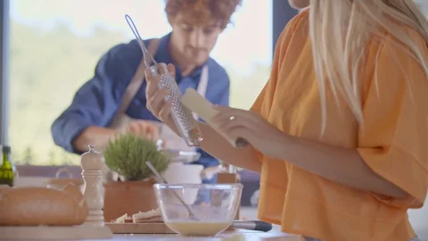 Man cooking and checking meal in modern kitchen.Woman grasping cheese.Young Vídeo Stock 129033087