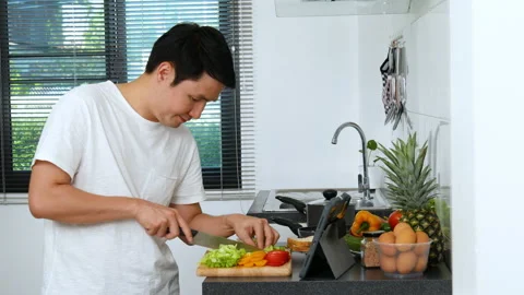Man cooking and preparing vegetables according to a recipe on a tablet computer  Video stock 170708835