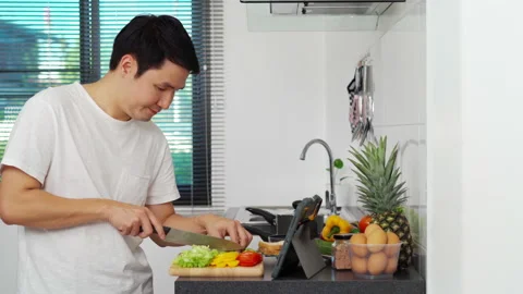 Man cooking and preparing vegetables according to a recipe on a tablet computer  Stock Footage 171402447