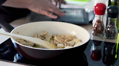 Man cooking chicken and checking recipe on tablet computer in kitchen at home HD Vídeos de archivo 49550188